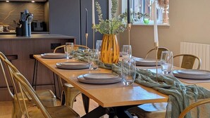 A modern dining area with a wooden table set for six, surrounded by chairs.