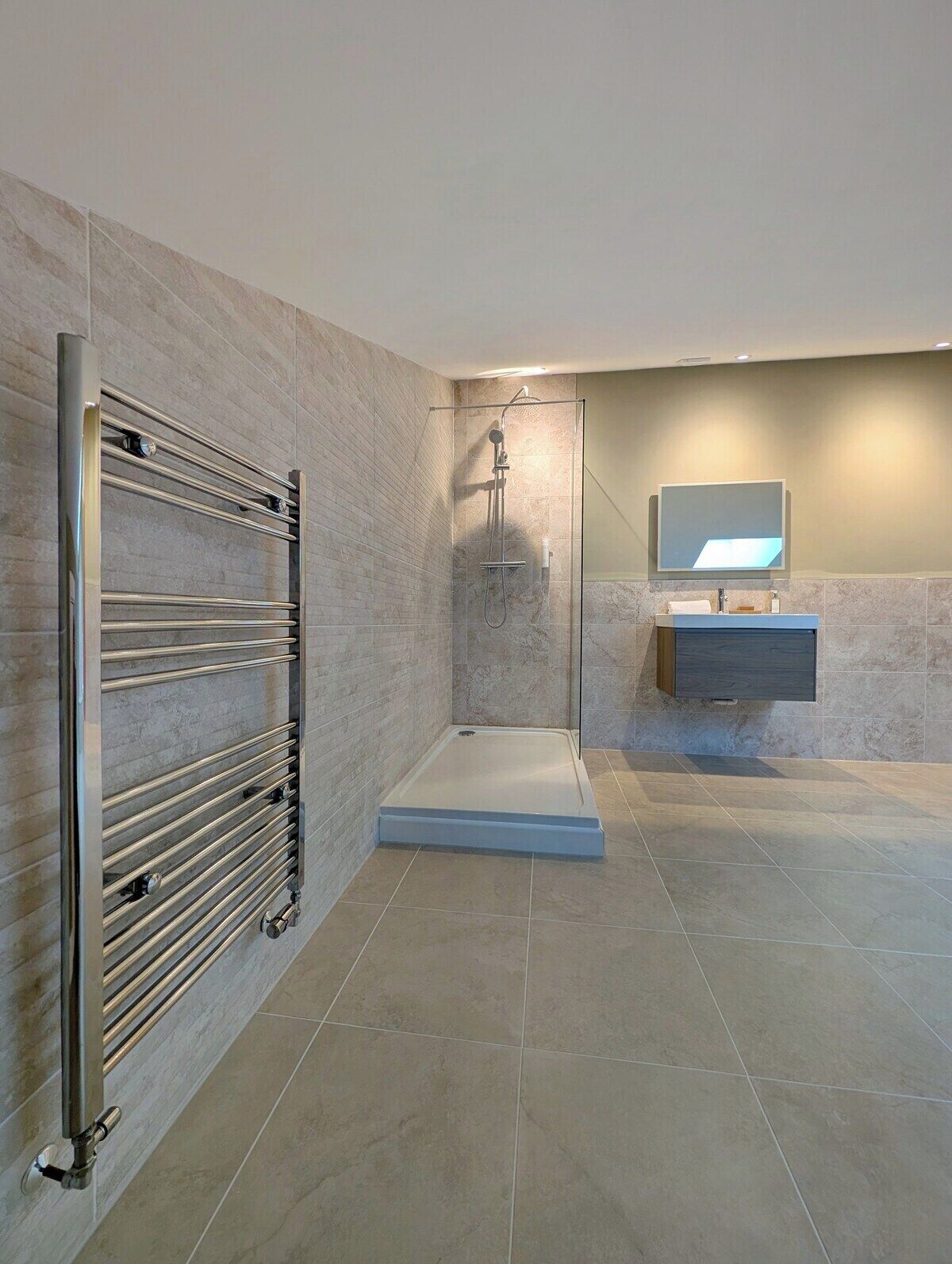 A modern bathroom with a walk-in shower, a glass-enclosed toilet, and a vanity with a mirror.