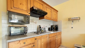 A kitchen with wooden cabinets, a microwave, a toaster, a sink, and a coffee maker. - Deluxe Apartment with Lake View K3 003 (Spalt)