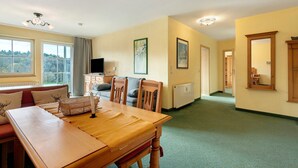 A dining area with a wooden table and chairs, a television, and a window with a view. - Deluxe Apartment with Lake View K3 003 (Spalt)