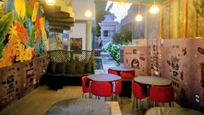 An indoor café with red chairs and tables, a mural on the left wall, and hanging lights. - De Glen Hotel And Suites (Owerri)