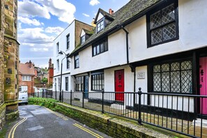 A narrow street with traditional buildings, including a white building with a red door and a sign that reads "Farmer's House." - Old Town Cottage, Hastings (Hastings)