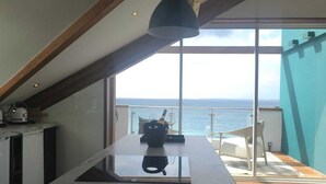 Una cucina moderna con una grande isola, travi in legno e vista sul mare.