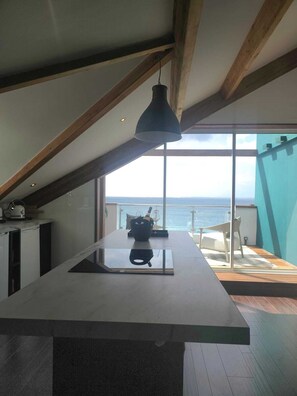 Una cocina moderna con una isla grande, vigas de madera y vista al mar.