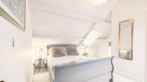 A bedroom with a bed, a mirror, a lamp, and a ceiling fan. - Cosy Cottage in Moreton-in-Marsh (Gloucestershire)