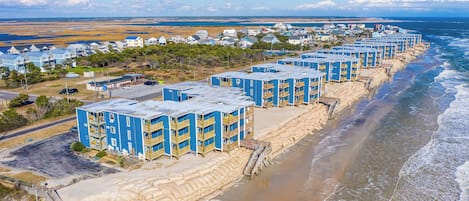 Een strandhotel met meerdere blauwe gebouwen, toegang tot een zandstrand en uitzicht op de oceaan.