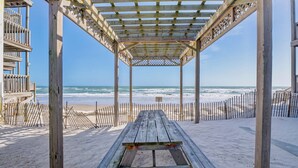 A wooden beach pavilion with a bench, overlooking the ocean. - Captain's Quarters | Oceanfront Condo (North Topsail Beach)