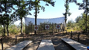 Un campo de tiro con arco al aire libre, con blancos y un sendero de madera.