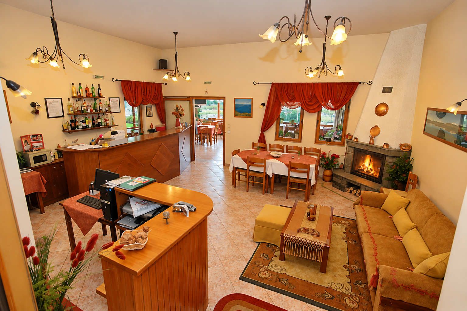 Un vaste espace de vie comprenant un coin salon avec cheminée, une table à manger et un bar avec des bouteilles.