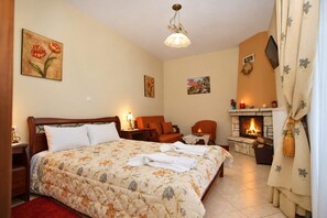 A bedroom with a bed, a chair, a fireplace, and a nightstand.