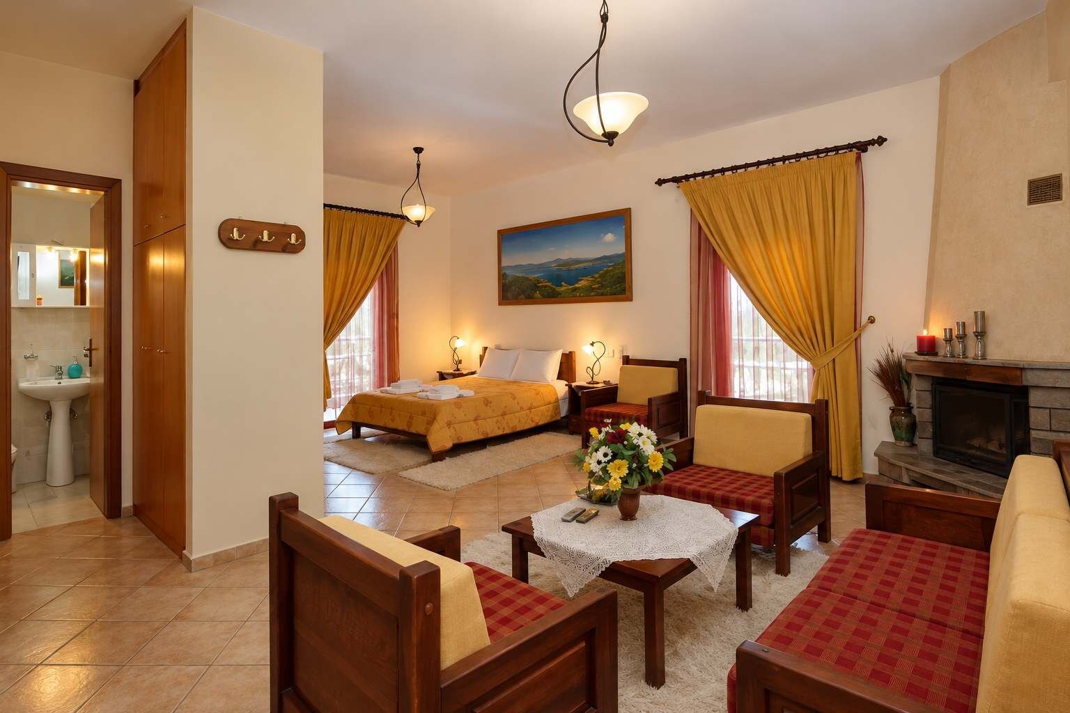 A hotel room with a bed, a sitting area with a table and chairs, a fireplace, and a painting on the wall.