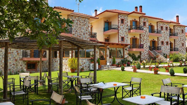 A courtyard with outdoor seating and a stone building with multiple balconies.
