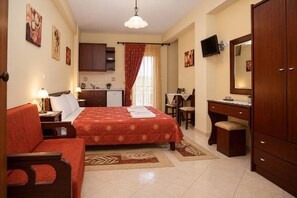 A hotel room with a bed, a desk, a chair, a wardrobe, and a television.