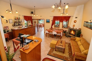A spacious living area with a fireplace, a dining table, and a bar area with bottles.