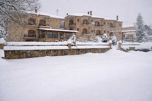 Un bâtiment en pierre doté de nombreux balcons, entouré de neige.
