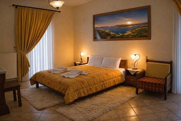 Une chambre d’hôtel avec un lit, deux lampes de chevet, une chaise, un tableau représentant un paysage et une fenêtre avec des rideaux.