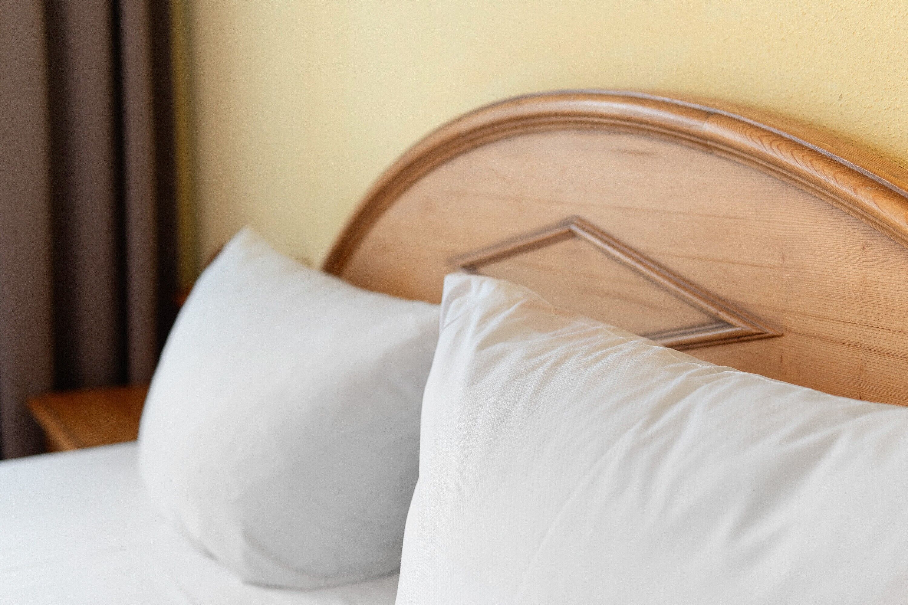 A bed with a wooden headboard and white pillows.