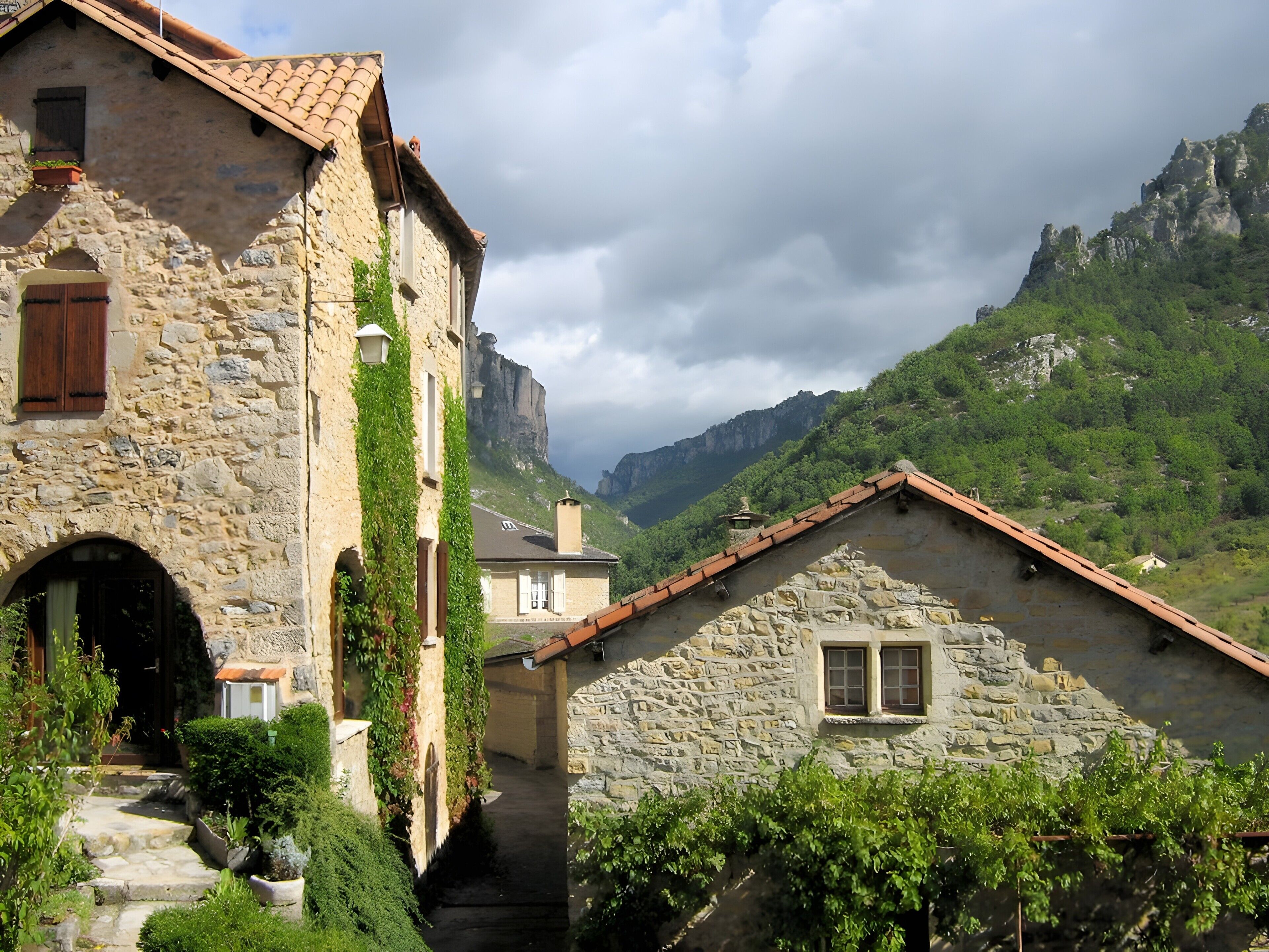 A stone building with a tiled roof, a narrow entrance, and a view of a mountainous landscape.