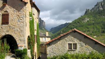 A stone building with a tiled roof, a narrow entrance, and a view of a mountainous landscape.