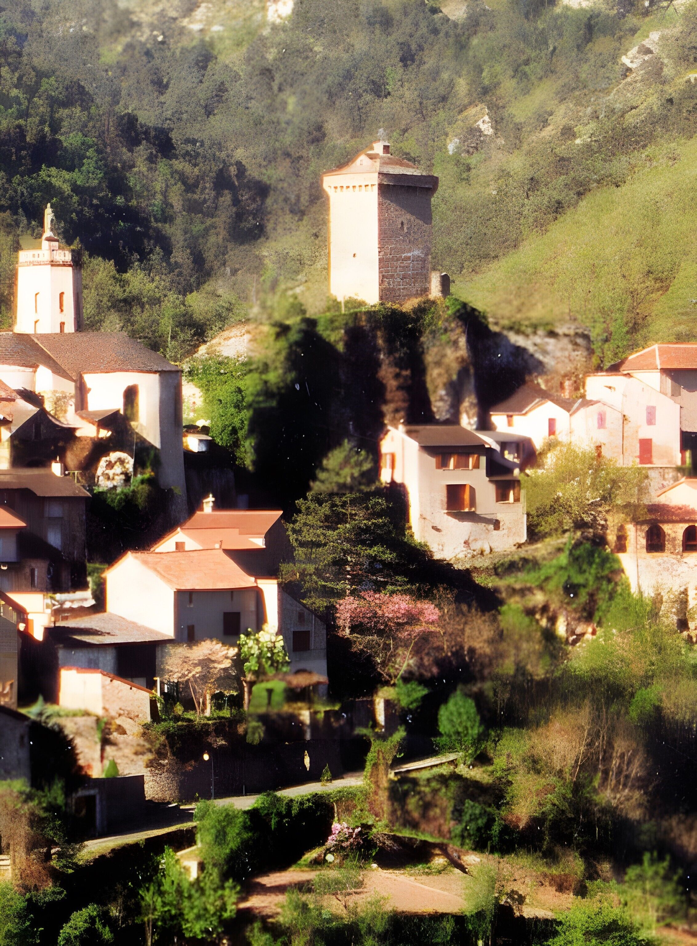 Uma aldeia na encosta com edifícios tradicionais, uma torre imponente e vegetação exuberante.