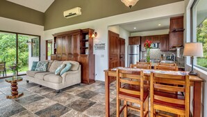 A spacious living area with a large sofa, wooden dining table, and a kitchen with modern appliances.