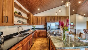 Una cocina moderna con armarios de madera, un refrigerador de acero inoxidable y una encimera de mármol.