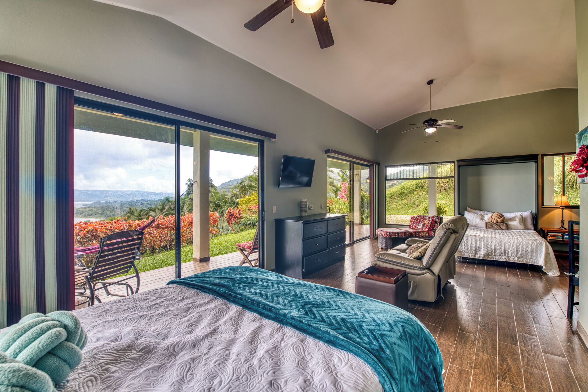 Une chambre spacieuse avec un grand lit, un coin salon et une vue sur un jardin luxuriant.