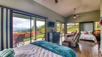 Une chambre spacieuse avec un grand lit, un coin salon et une vue sur un jardin luxuriant.