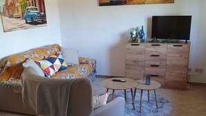 Un salon comprenant un canapé, une table basse, un téléviseur et un meuble.