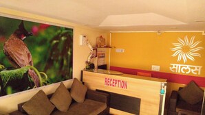 Un espace d’accueil avec un comptoir en bois, une enseigne fixée au mur indiquant « RÉCEPTION » et une grande affiche représentant un oiseau.