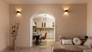 A modern living room with a beige sofa, a dining area with a table and chairs, and a kitchen visible through an archway. - Solitude in Ružići - Istrien / Solitude in Ružići - Appartement für 4 Personen (Ružići)
