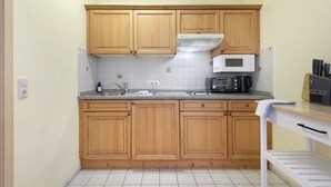 A kitchen with wooden cabinets, a microwave, a sink, and a countertop. - Superior Apartment with Dog – Lake View, Balcony, Self Check-in (Spalt)