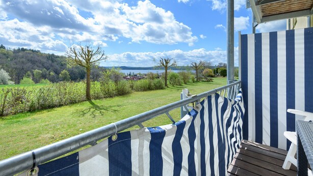 A balcony with a view of a grassy area and trees, a metal railing, and a wooden deck. - Superior Apartment with Dog – Lake View, Balcony, Self Check-in (Spalt)