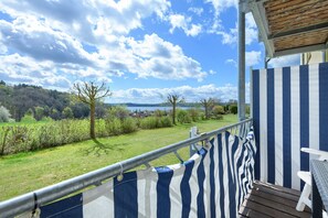 Ein Balkon mit Blick auf eine Rasenfläche und Bäume, einem Metallgeländer und einem Holzboden.