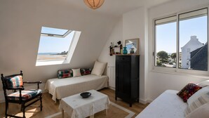 Ein Schlafzimmer mit Bett, Sessel, Tisch, Kleiderschrank und Fenster mit Blick auf den Strand.
