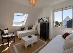Une chambre à coucher comprenant un lit, une chaise, une table, une armoire et une fenêtre donnant sur la plage.