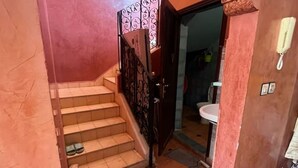 A staircase with a metal railing leading to a room with a sink and a door. - Relaxing getaway in Ourika - Small villa with garden (Marrakech)