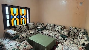 A room with a patterned sofa set, a small table, and a window with a geometric stained glass design. - Relaxing getaway in Ourika - Small villa with garden (Marrakech)