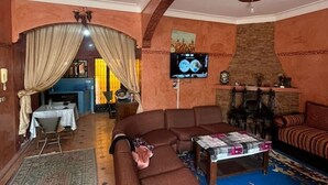 A living room with a sofa, a coffee table, a TV, and a fireplace. - Relaxing getaway in Ourika - Small villa with garden (Marrakech)