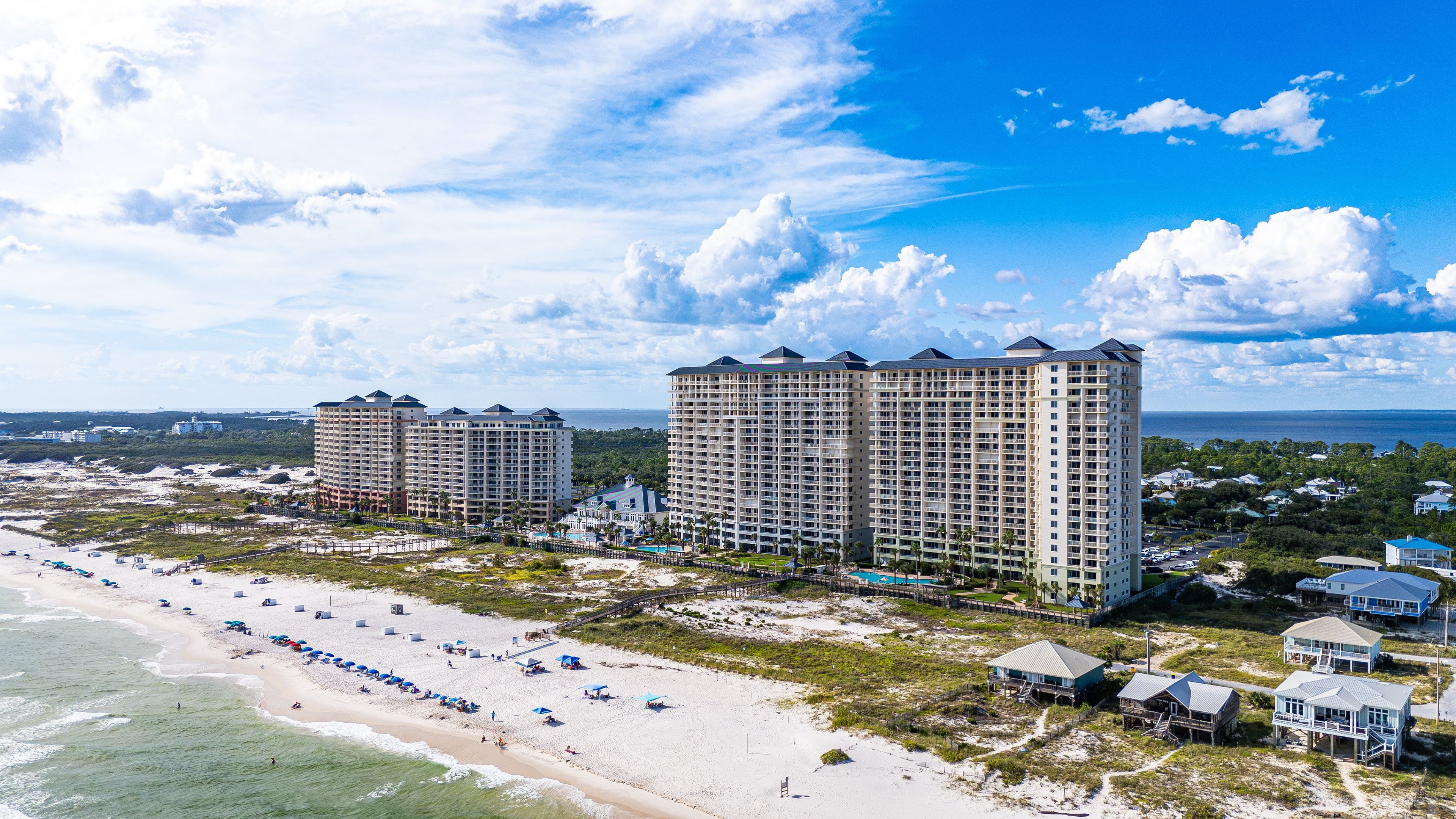 Ein Strandhotel mit mehreren Hochhäusern, einem Sandstrand und freiem Blick auf den Ozean.