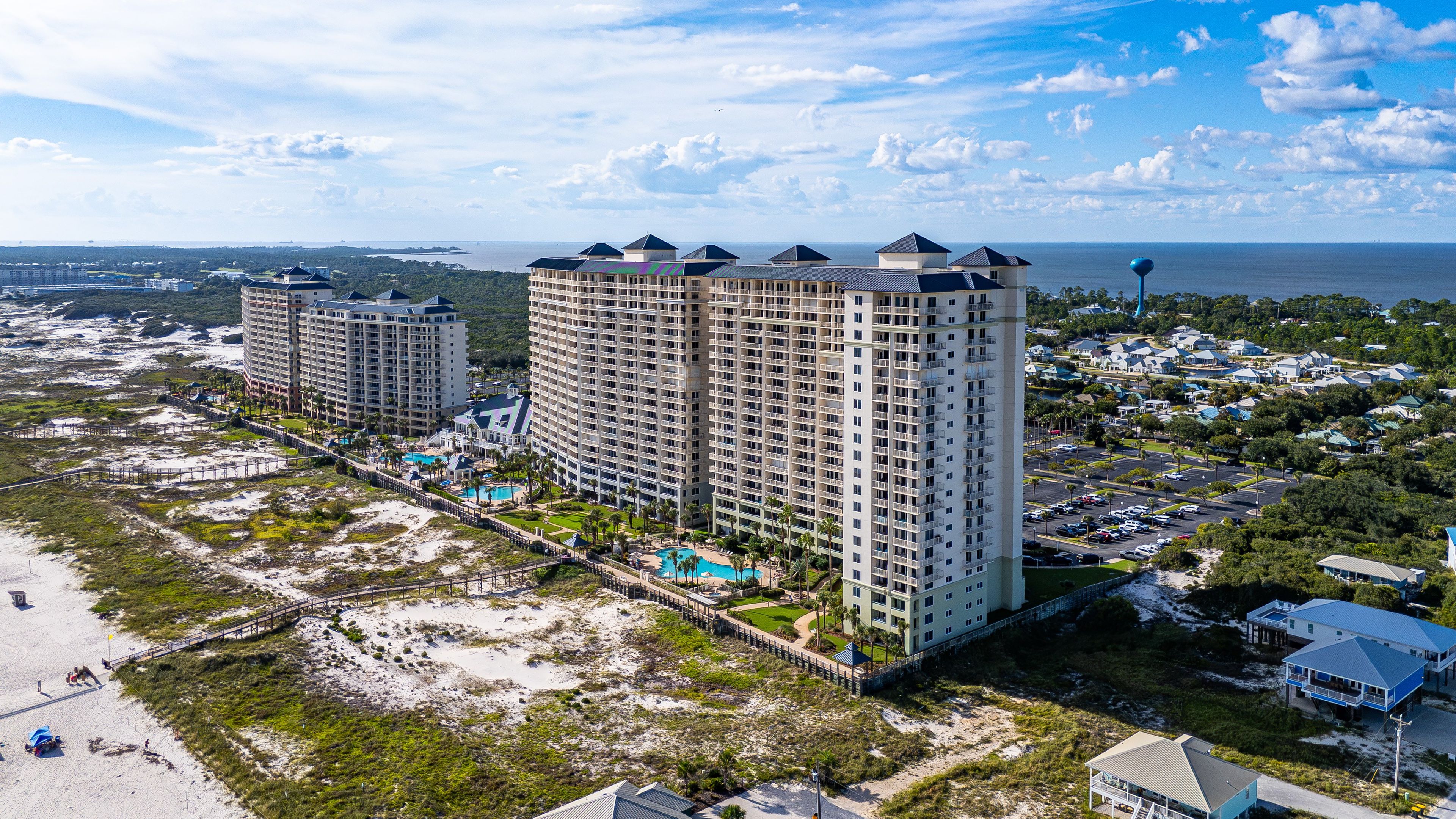 A high-rise hotel with multiple floors, a pool area, and a beach view.