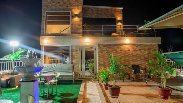 A two-story house with a balcony, outdoor seating, and potted plants.