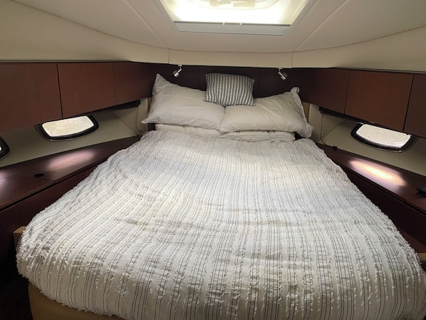 A bed with a striped bedspread, two pillows, and bedside tables with lamps.