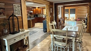 Un coin repas avec une table et des chaises en bois, une cuisine en arrière-plan et une décoration intérieure de style rustique.