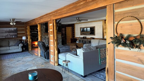 Un salon chaleureux avec une cheminée en pierre, des poutres en bois et un grand téléviseur.