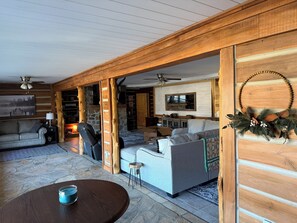 Una sala de estar acogedora con chimenea de piedra, vigas de madera y un televisor grande.