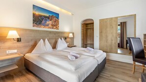 A hotel room with a large bed, two bedside tables, a wall-mounted lamp, a painting, a mirror, and a wooden wardrobe. - Double Room 1 at Gästehaus Elisabeth with Mountain View, Shared Pool and Wi-Fi (Löbenau)