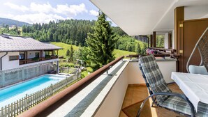 A balcony with a view of a swimming pool, a chair, and a table. - Double Room 1 at Gästehaus Elisabeth with Mountain View, Shared Pool and Wi-Fi (Löbenau)
