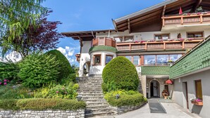 A multi-story building with a green roof, a balcony with flowers, and a stone staircase leading to the entrance. - Double Room 1 at Gästehaus Elisabeth with Mountain View, Shared Pool and Wi-Fi (Löbenau)