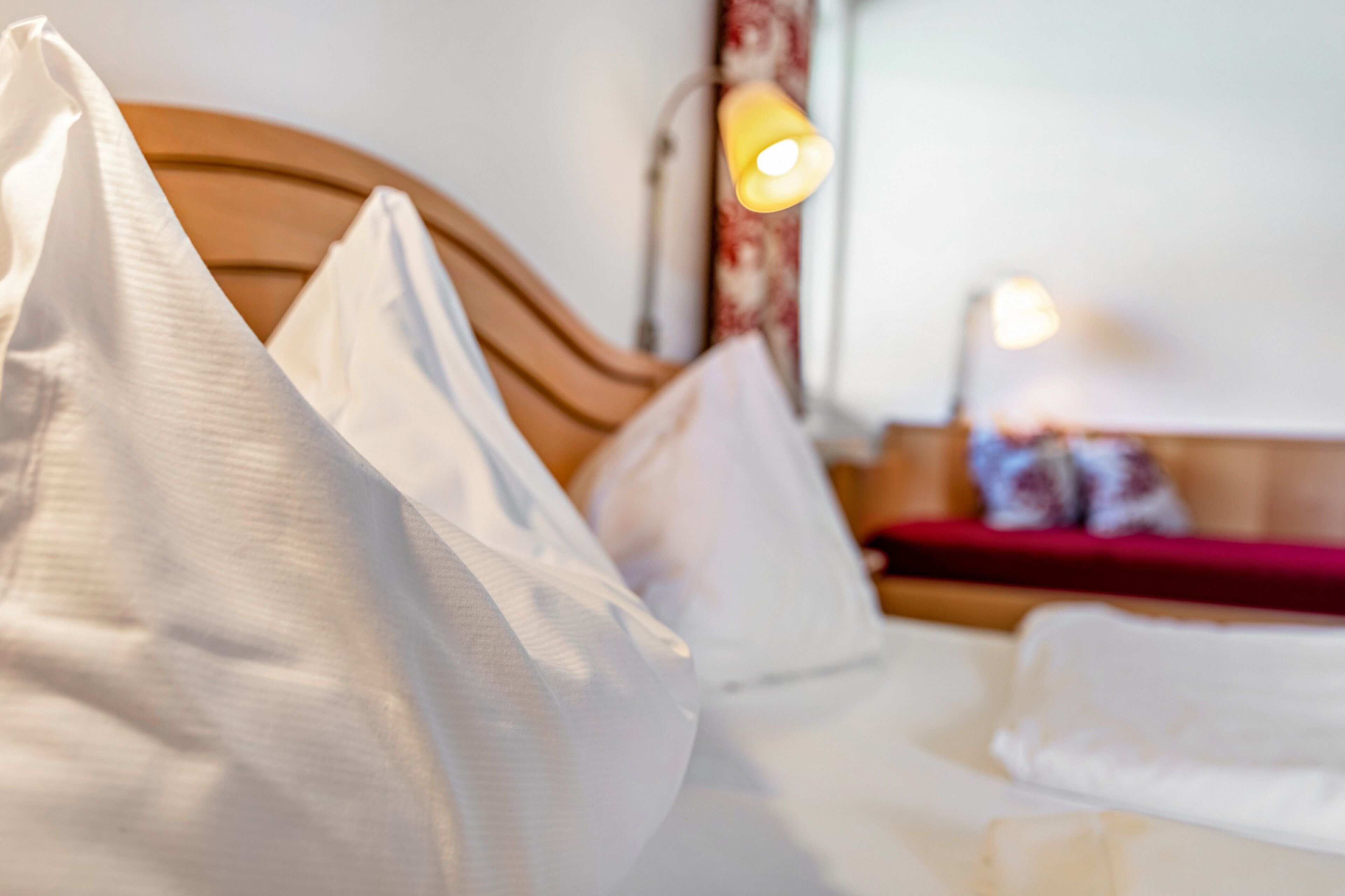 Ein Bett mit weißer Bettwäsche und einem Holzkopfende.